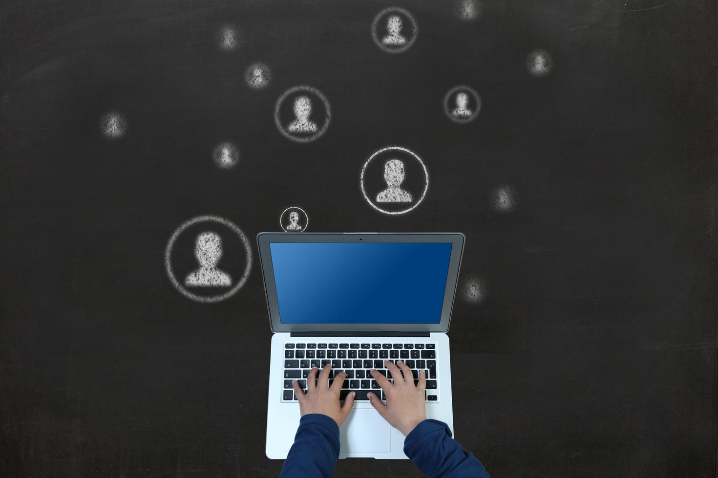 Person typing at a computer with white outlines of people around it on black background