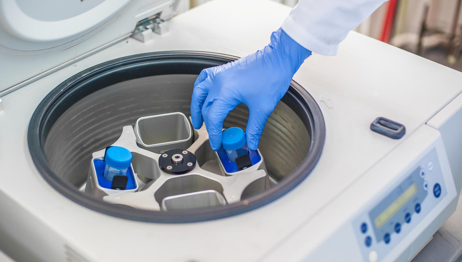 Technician loading a sample to centrifuge machine in a scientific laboratory 
