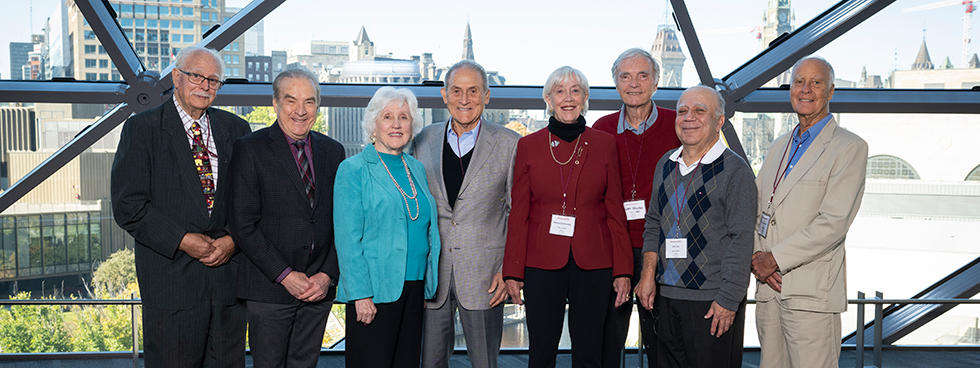 a group of people pose in the Shaw Centre in front of a view of Parliament Hill