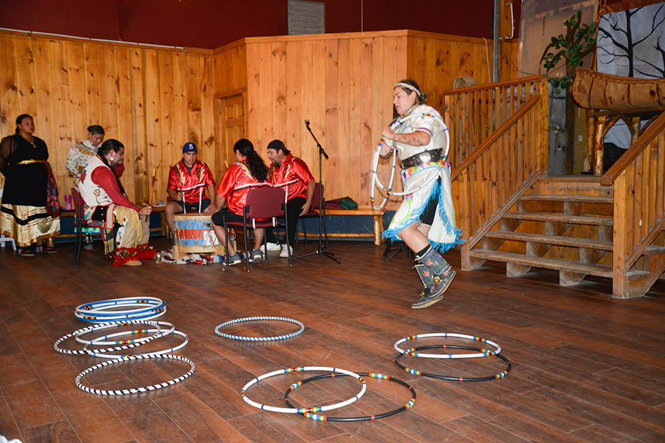 an Indigenous hoop dancer dancing for an audience.