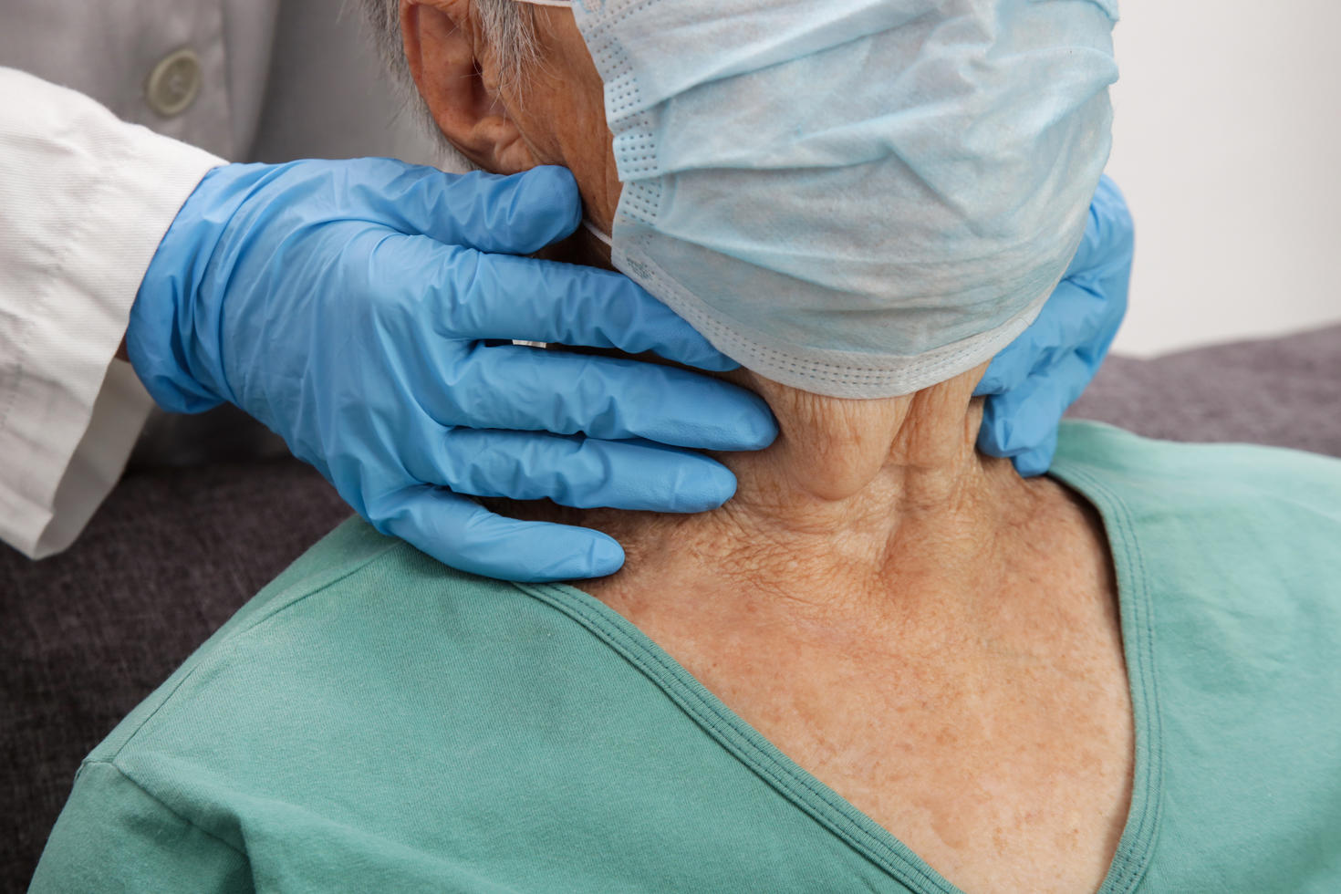 Doctor examining senior woman's thyroid glands or tonsils.