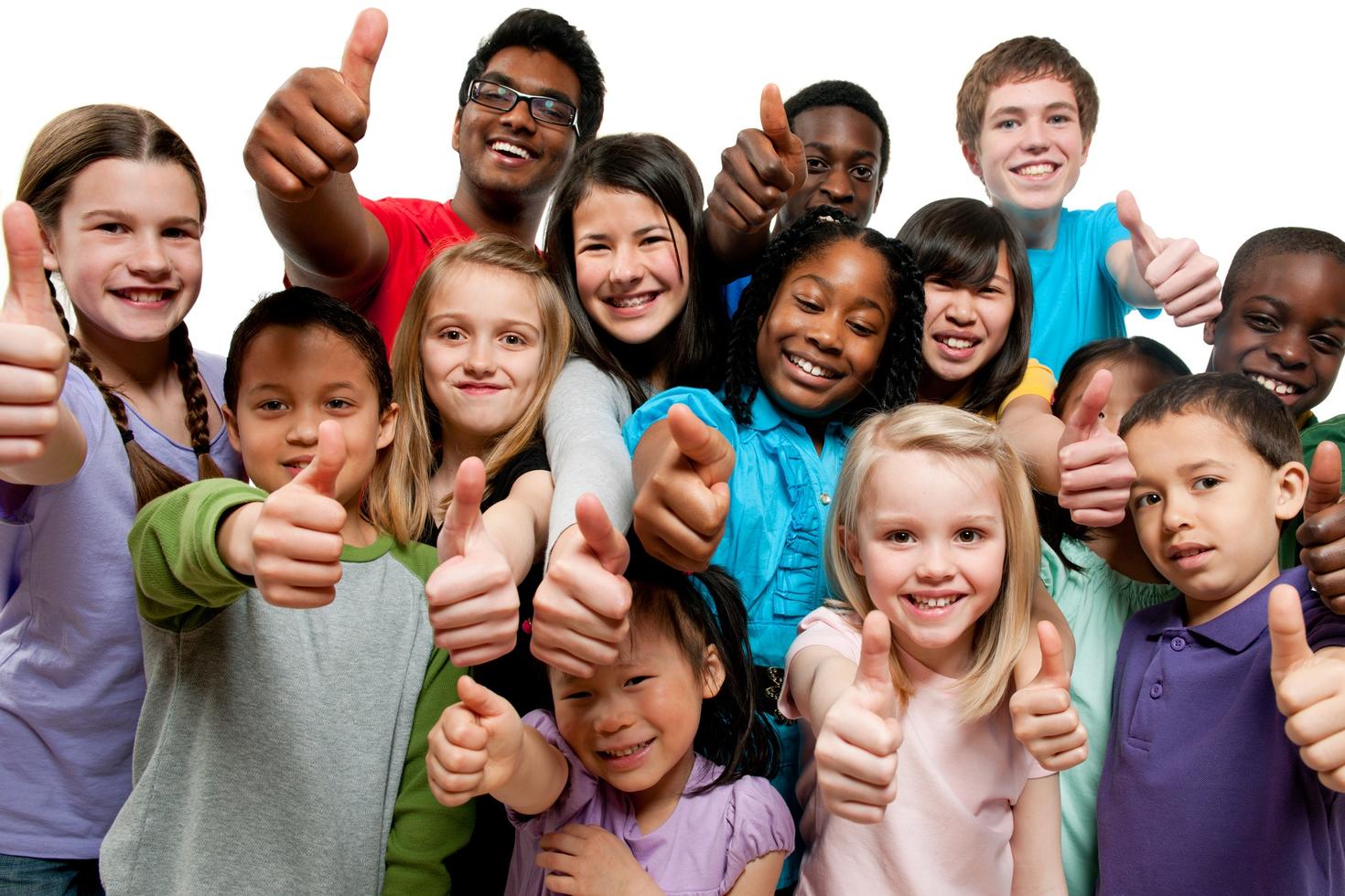 A group of K through grade 12 children standing together giving a thumbs up.