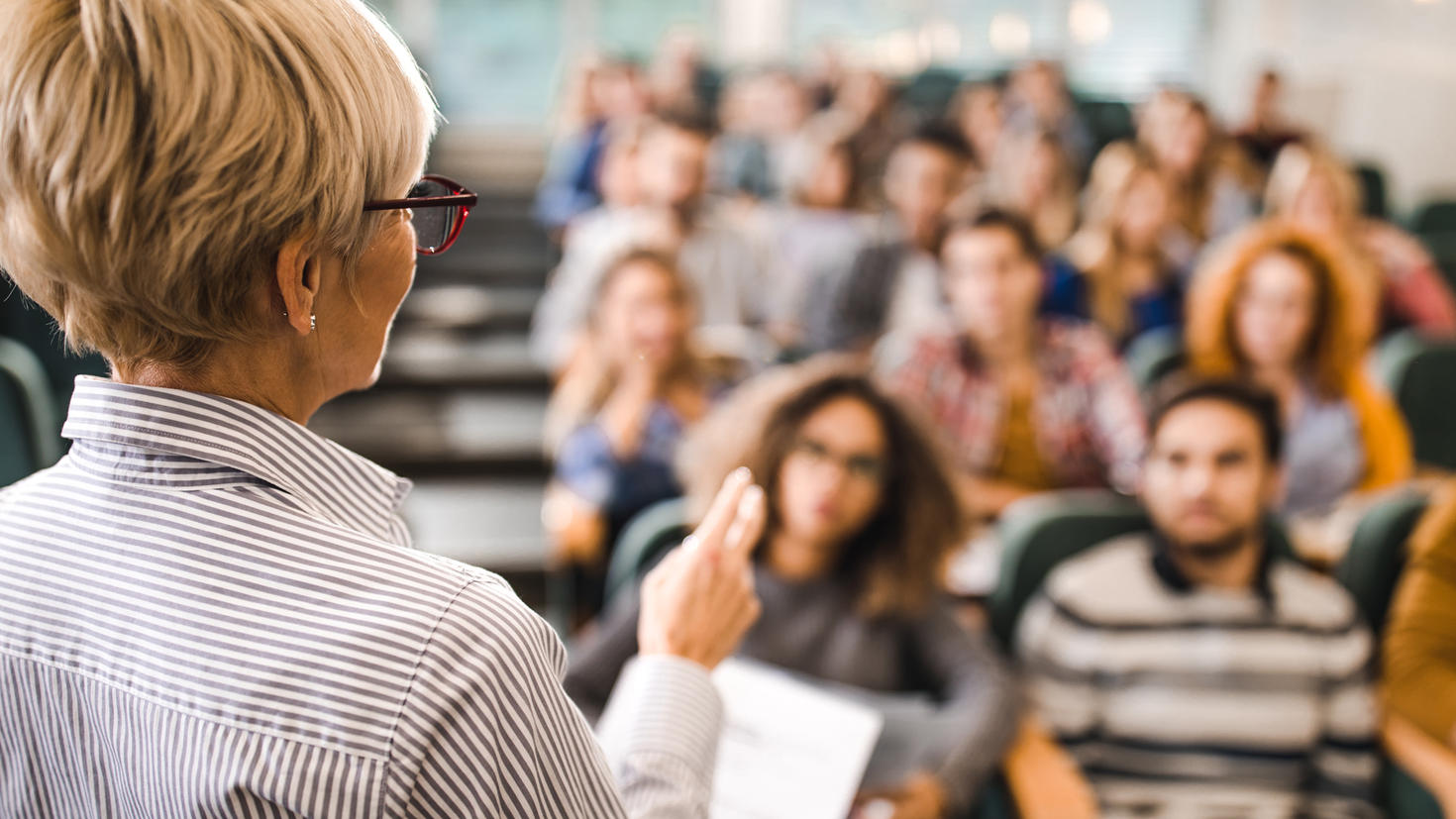 Rear view of mature teacher fiving a lecture in a classroom