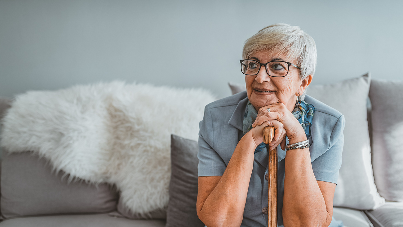 Senior gray hair women supporting on a walking cane at home.