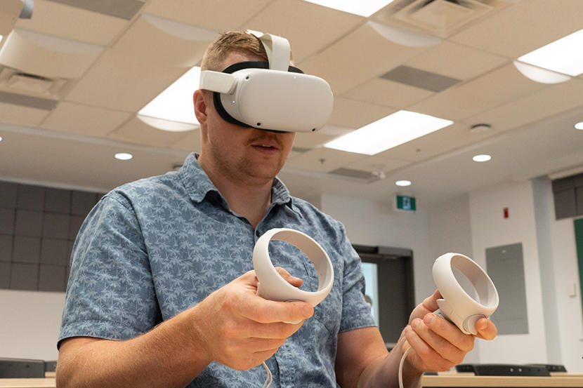 A person uses hand crontrollers while wearing a virtual reality headset
