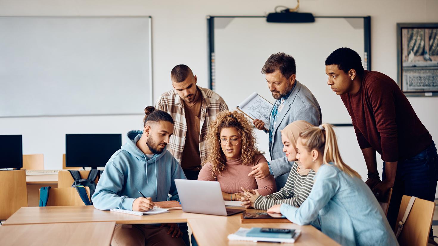 University teacher and his students using laptop in the classroom