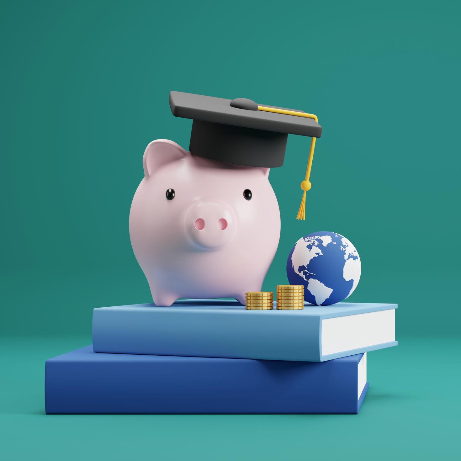 Piggy bank with graduation hat on book