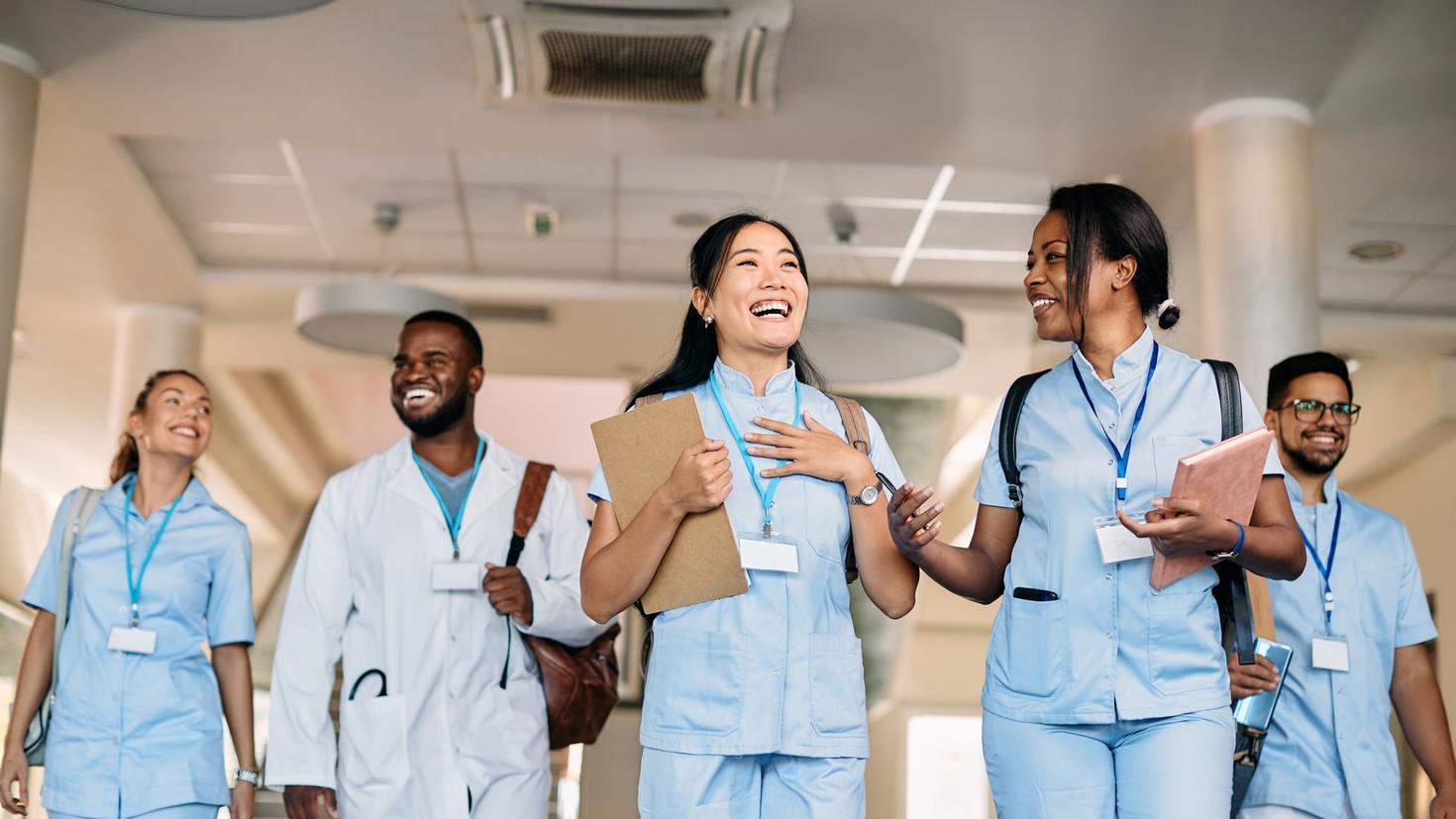 Happy multi-ethnic group of medical research students having fun while talking in a hallway at the university