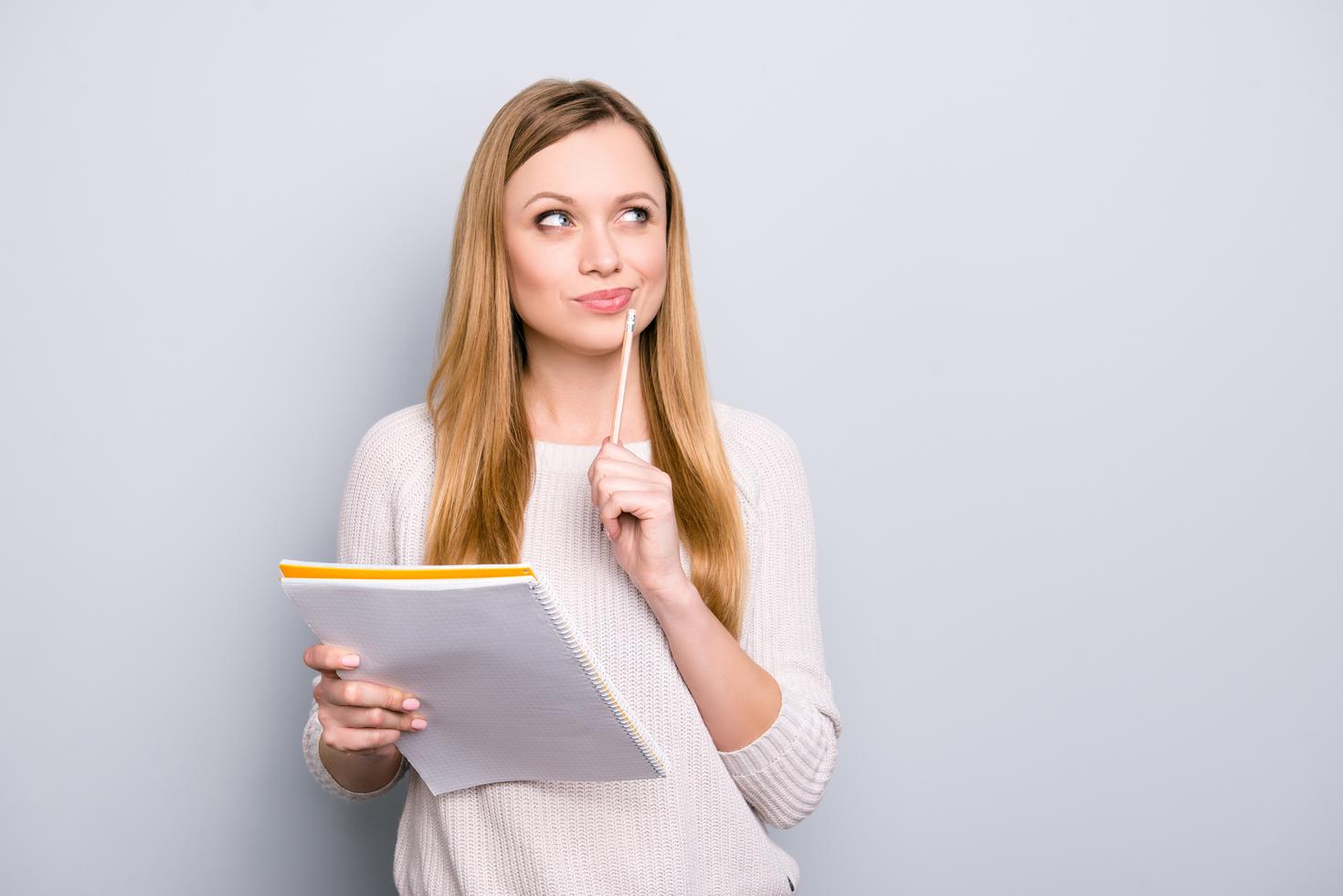 Pensive woman holding a notepad and pencil