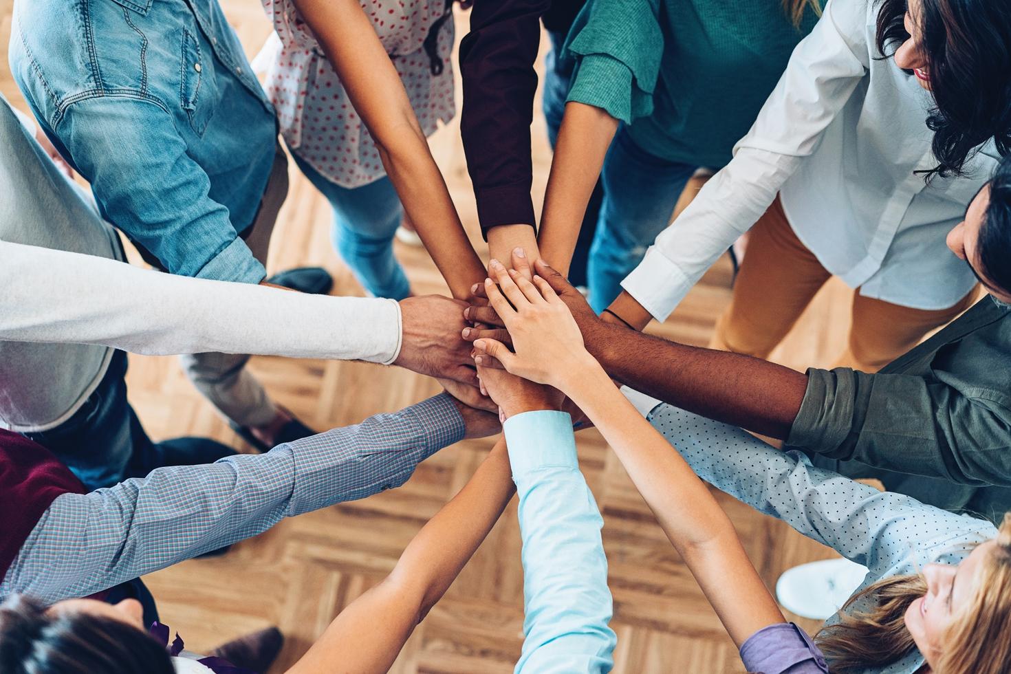 a group of people standing in a circle putting their hands together in the middle