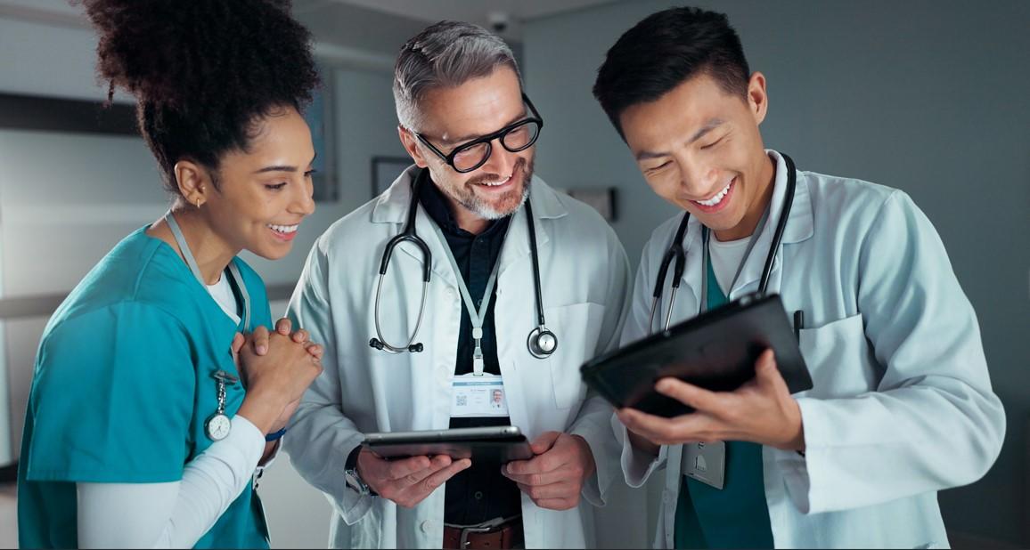 three health care workers smiling as they look at a tablet