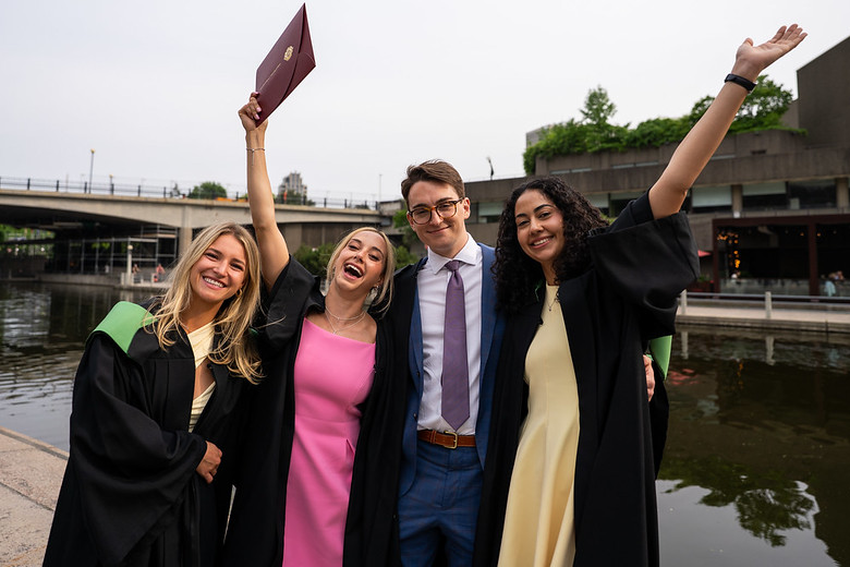 Four medical graduates smiling and waving their arms