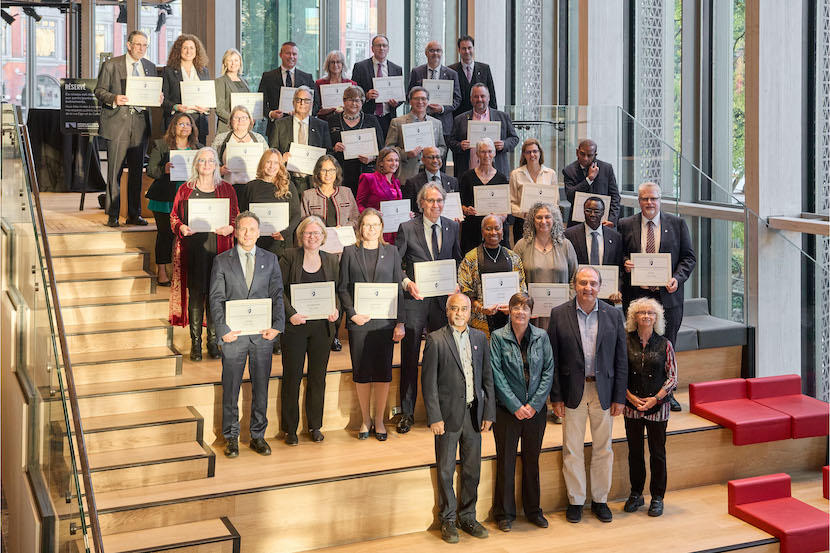 A group of people holding certificates behind a group of leaders.