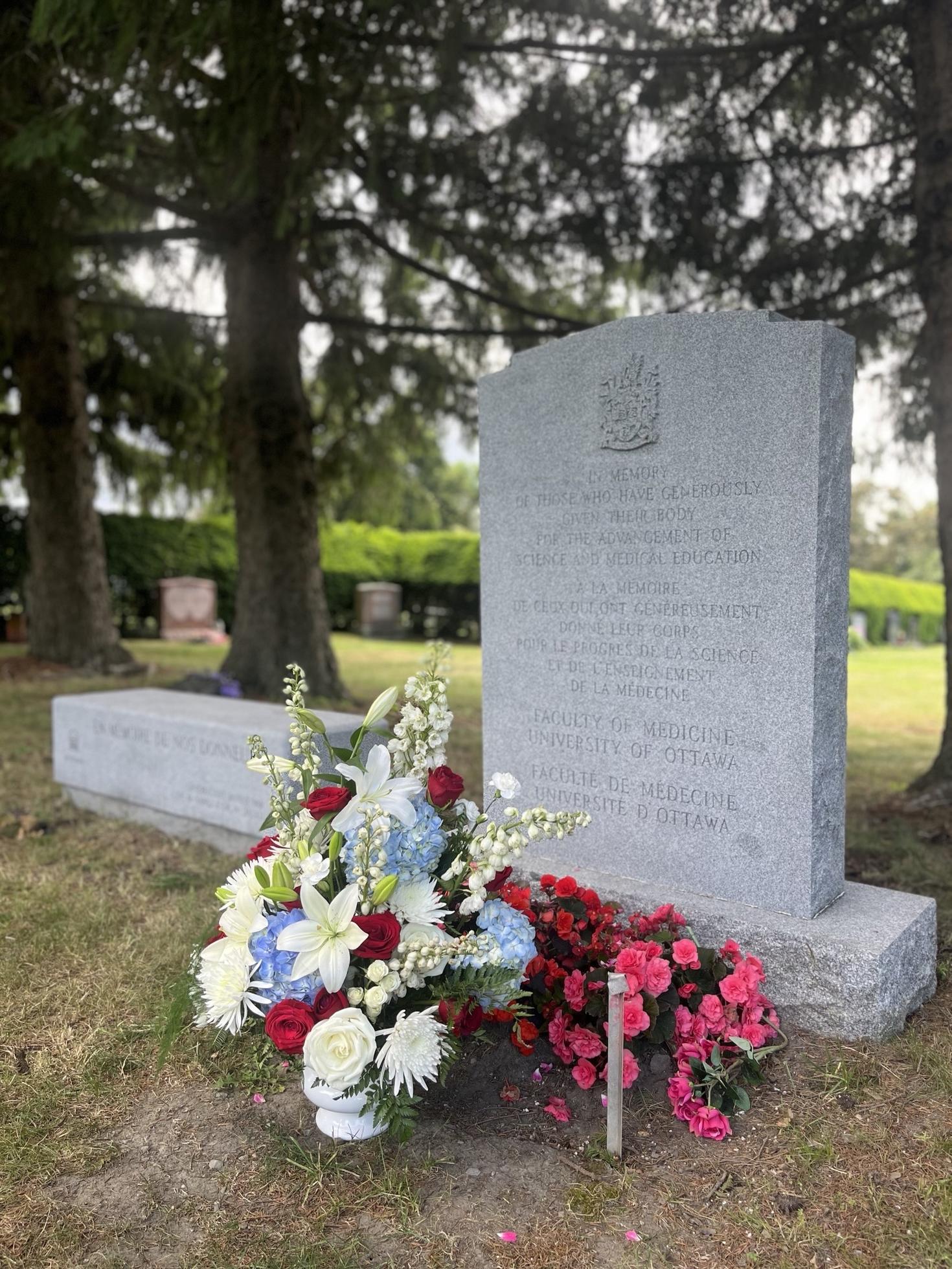 The Pinecrest Cemetery memorial stone adorned with flowers.