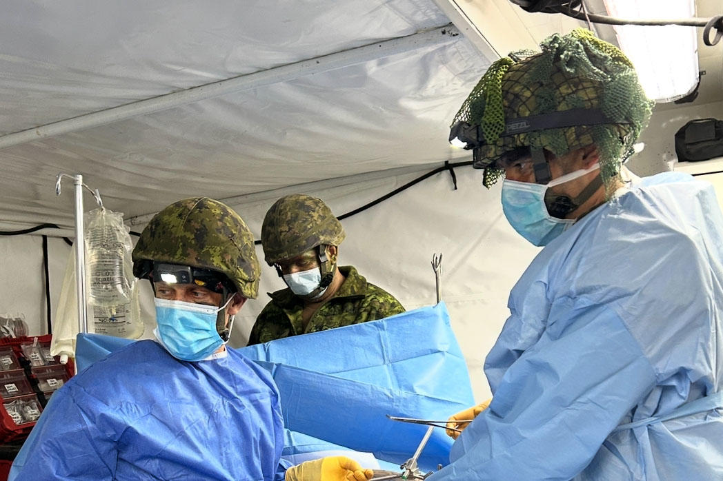 Dr. Alenko Šakanović performs surgery on a simulated patient while dressed in a surgeon's gown over a military uniform.