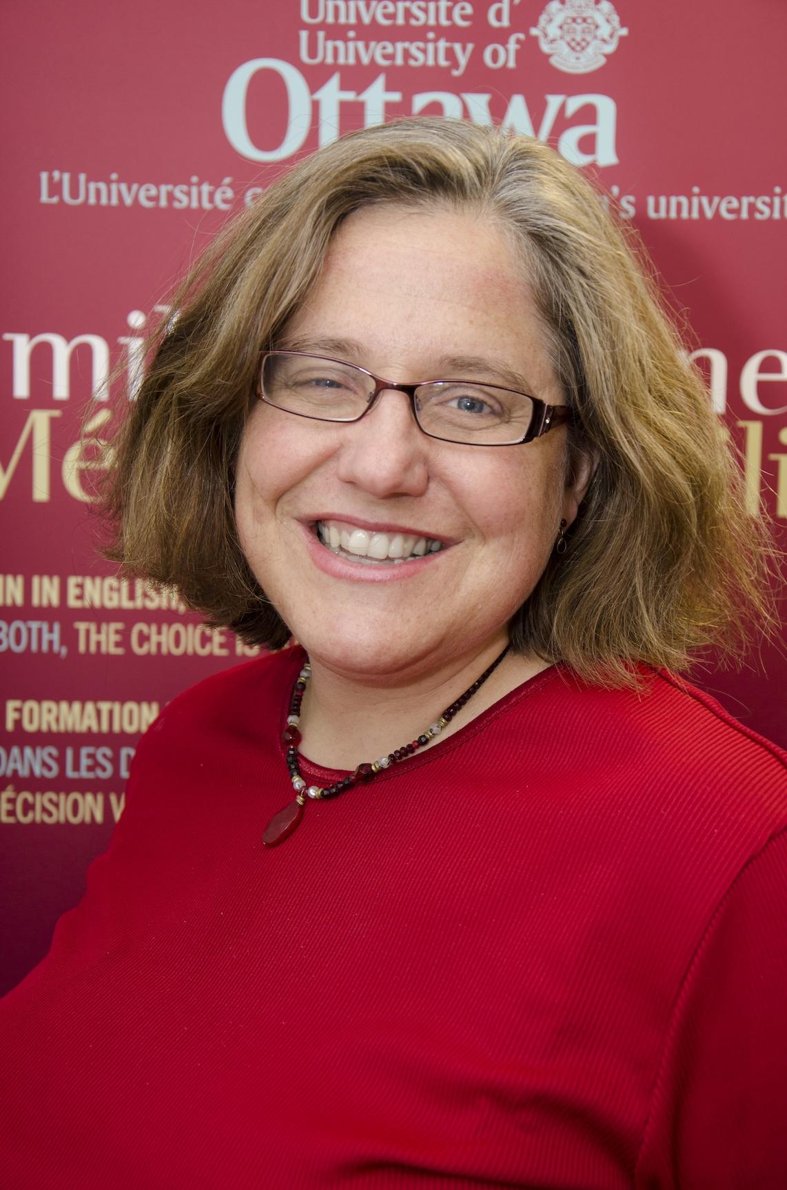 Dr. Carol Geller wearing a red sweater and glasses over a University of Ottawa background banner