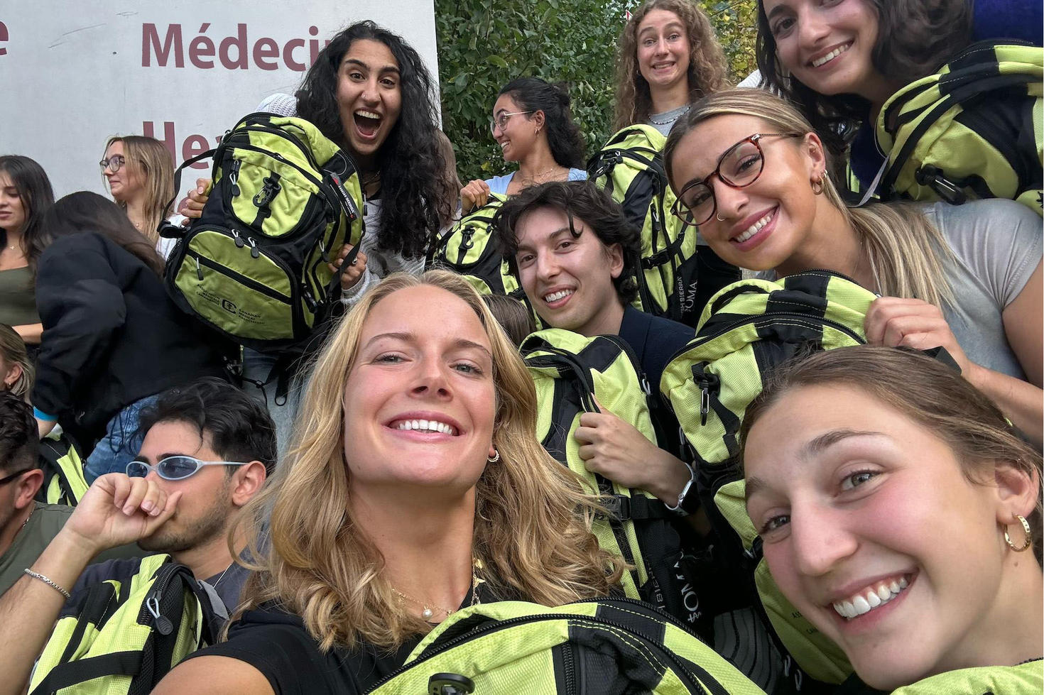 A group of francophone students laughing together and holding new backpacks
