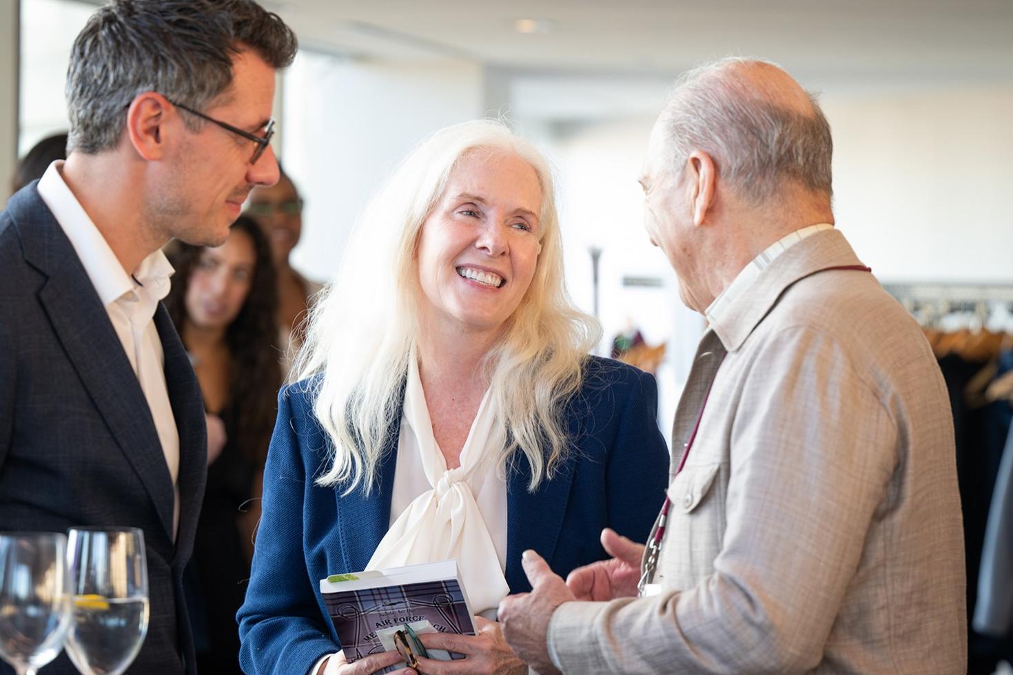 Dr. Pierre Morisset offering Dean Dr. Melissa Forgie a book documenting her father’s career as a military physician.