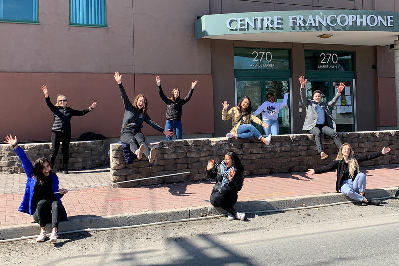 Medical students and administrators pose outside on the sidewalk.