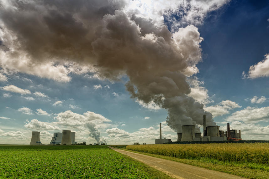 A view of a factory spewing pollution into a clear blue sky.