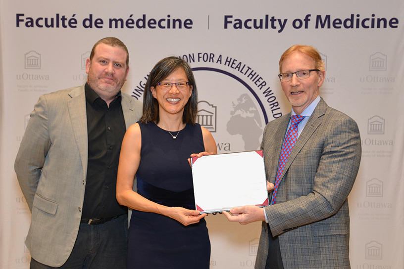 A man presents an award to a woman while another man watches.