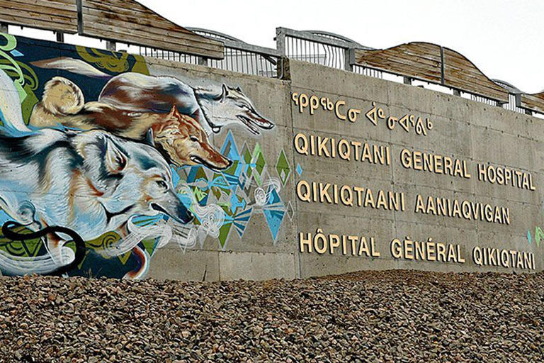 A wall outside the Qikiqtani General Hospital depicting a mural and the name of the hospital