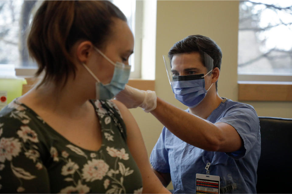 a man gives a vaccine to a woman