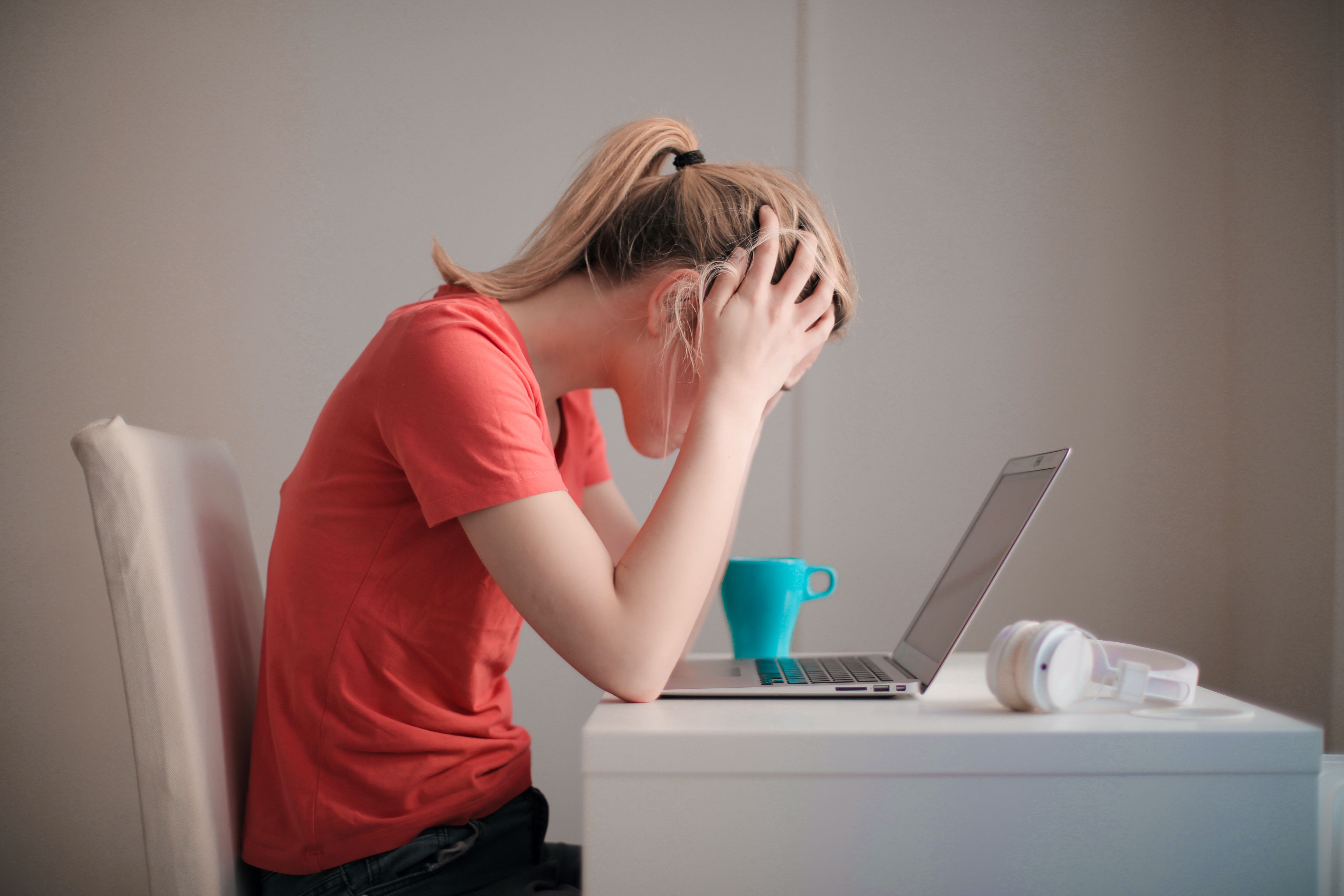 Student over a laptop holding her head