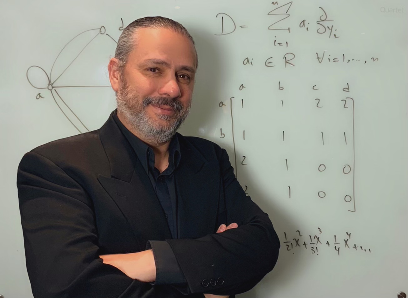 Joseph Khoury in front of a white board with mathematical equations.