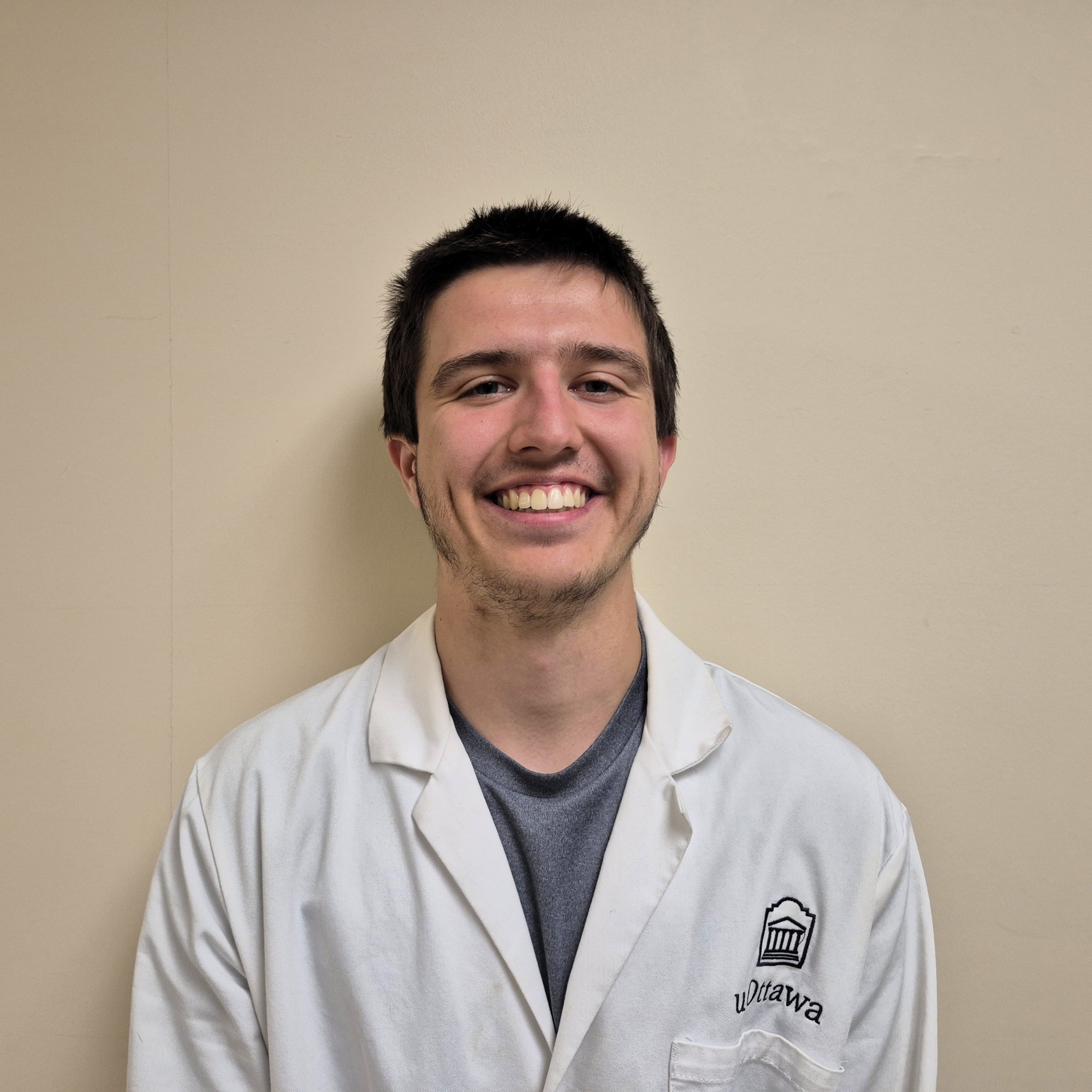 Quinn Murray wearing a lab coat posing in front of a wall.