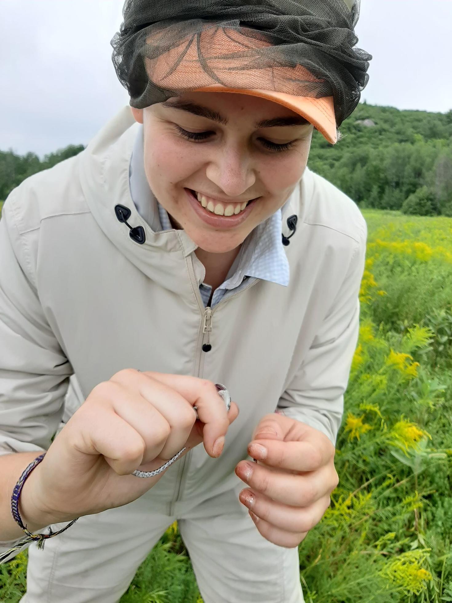 Coop student working in the field holding a smal reptile