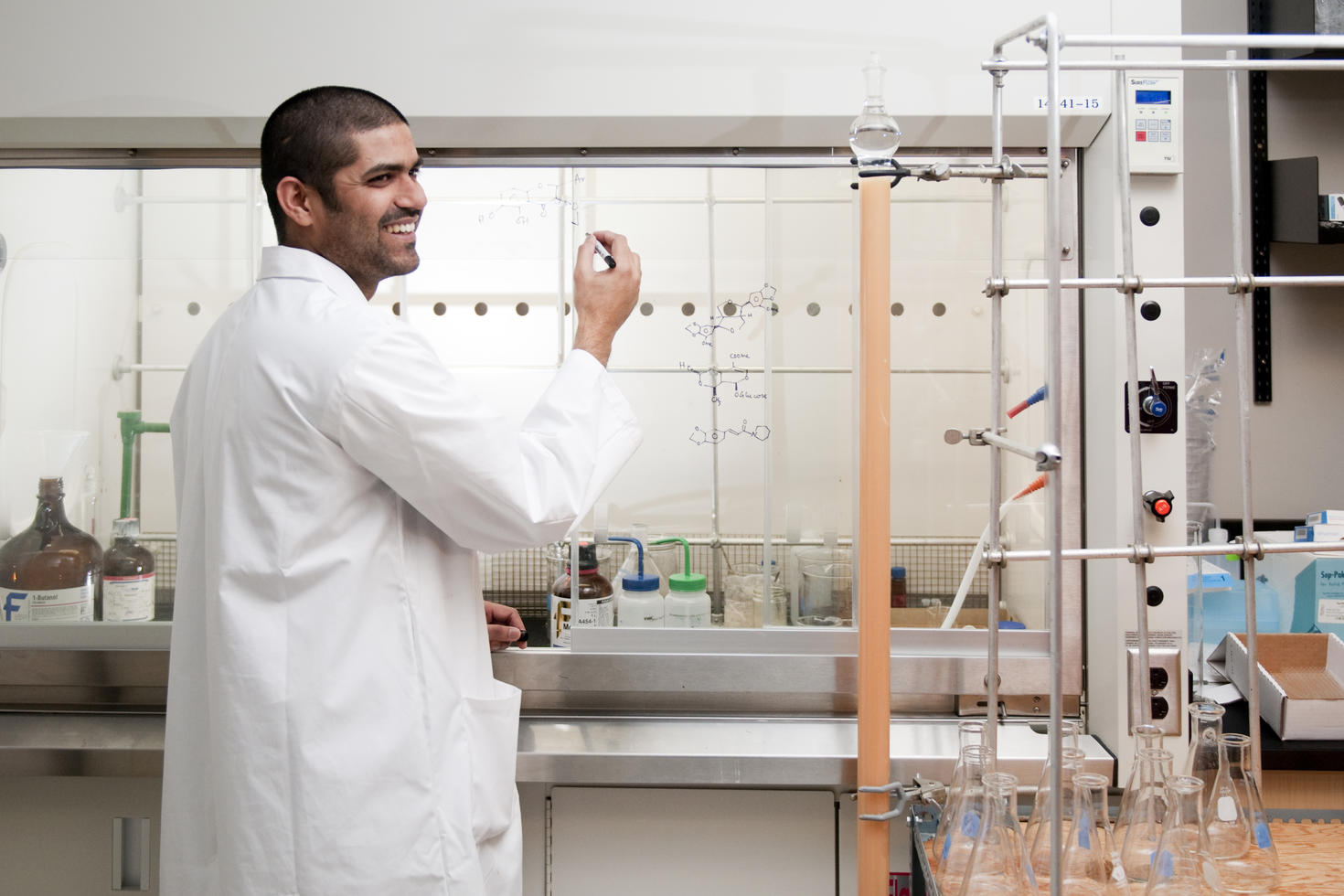 Student writing on a glass in a lab
