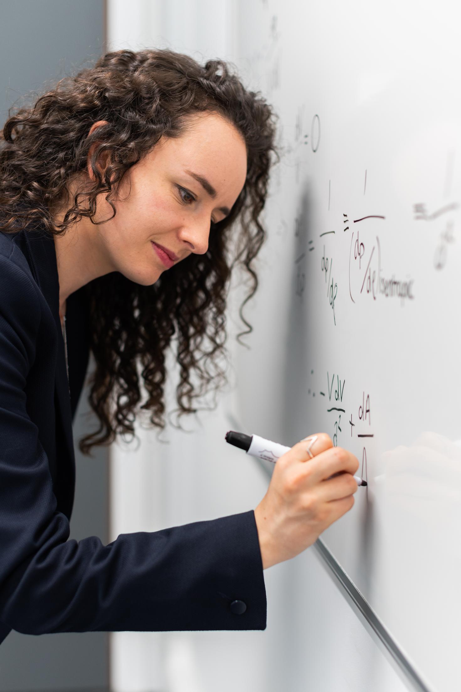 Mathematician writing equations on a white board