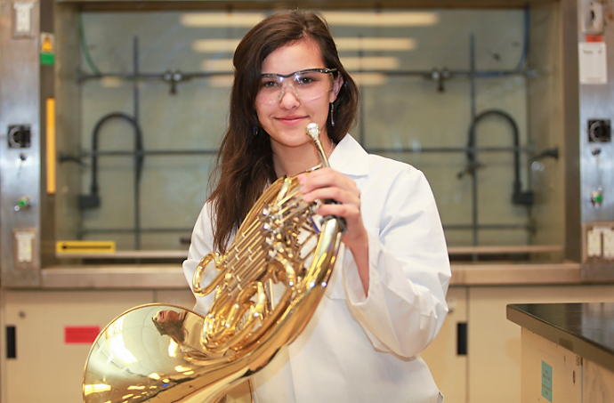 Female student with her music instrument in a science lab