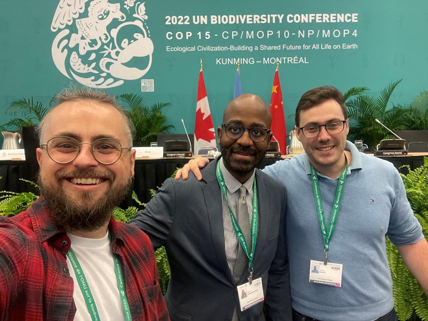 Three members of the CELGS delegation at COP 15 smiling in front the conference's banner