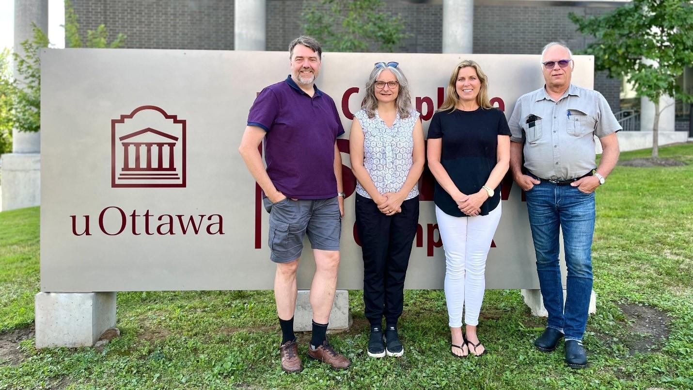 Professor Paul Mayer, Dr. Sharon Curtis, Deborah Quail-Blier, and Dr. Alexander Mommers, standing side by side in front of the uOttawa STEM complex sign