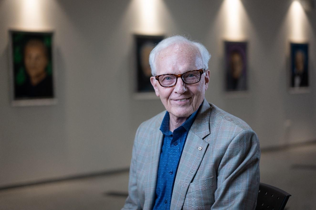 Professor Paul Corkum smiling in front of a gallery wall. 