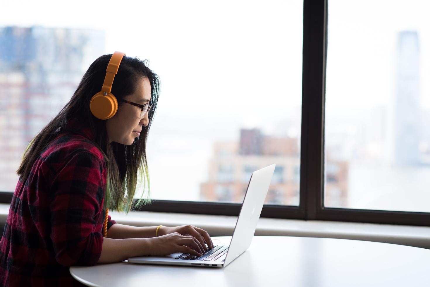 student working on her computer with headphones on