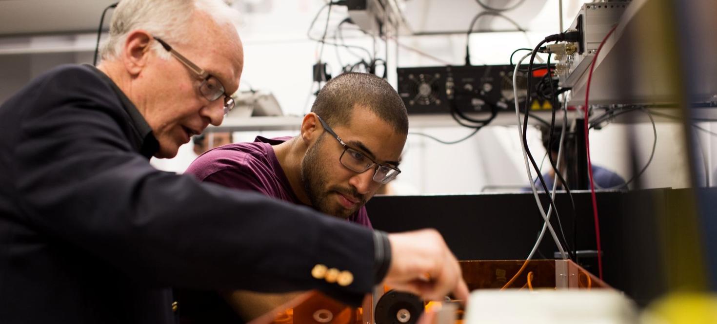 Prof. Paul Corkum showing physic equipment to a student