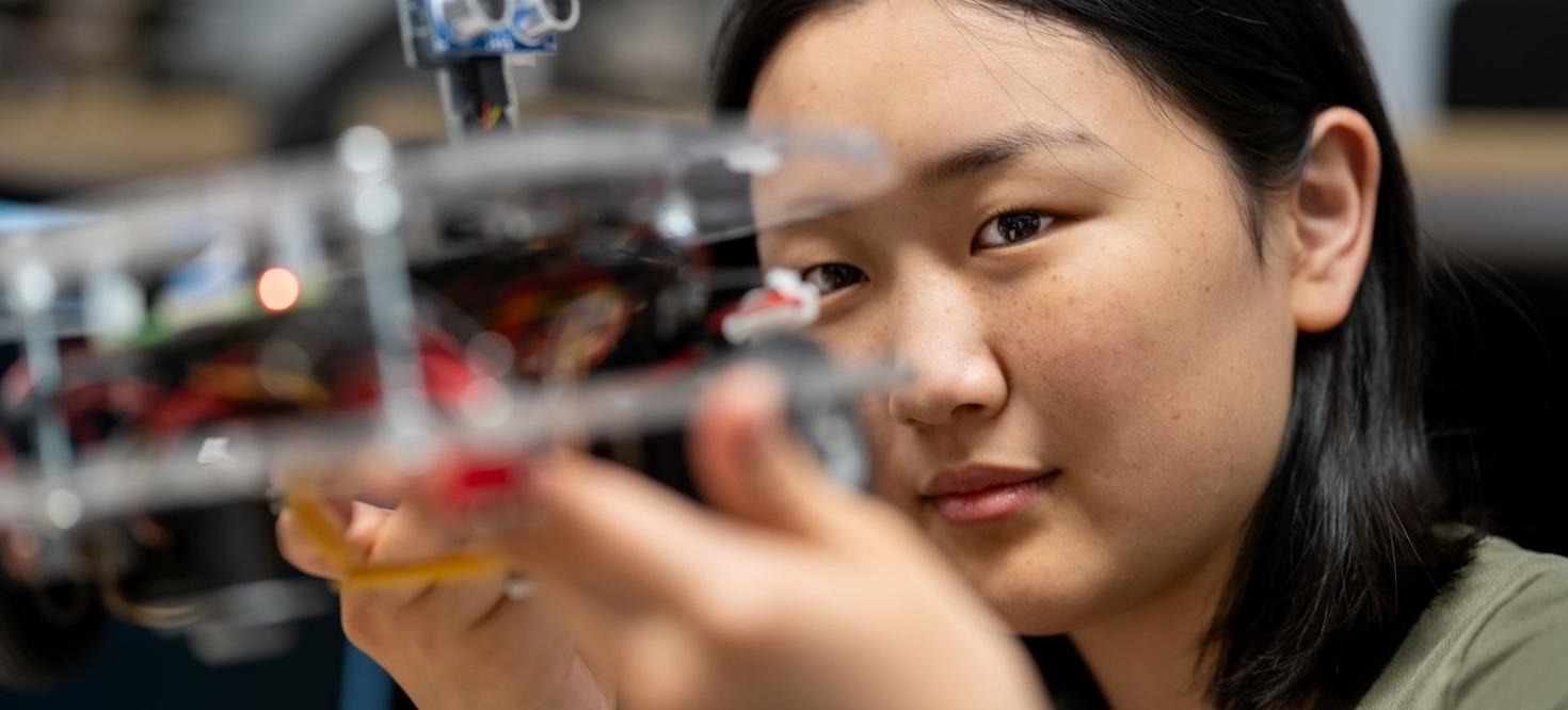Female student looking upclose to electronics equipment