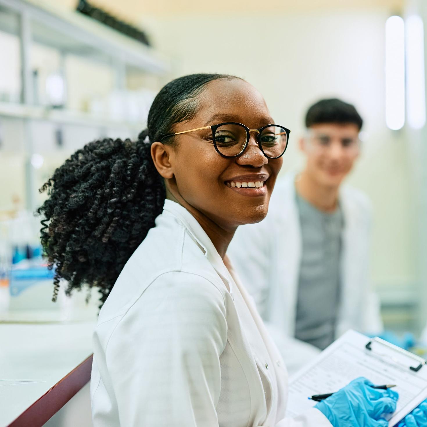 Female student holding a lab report and smiling in a lab