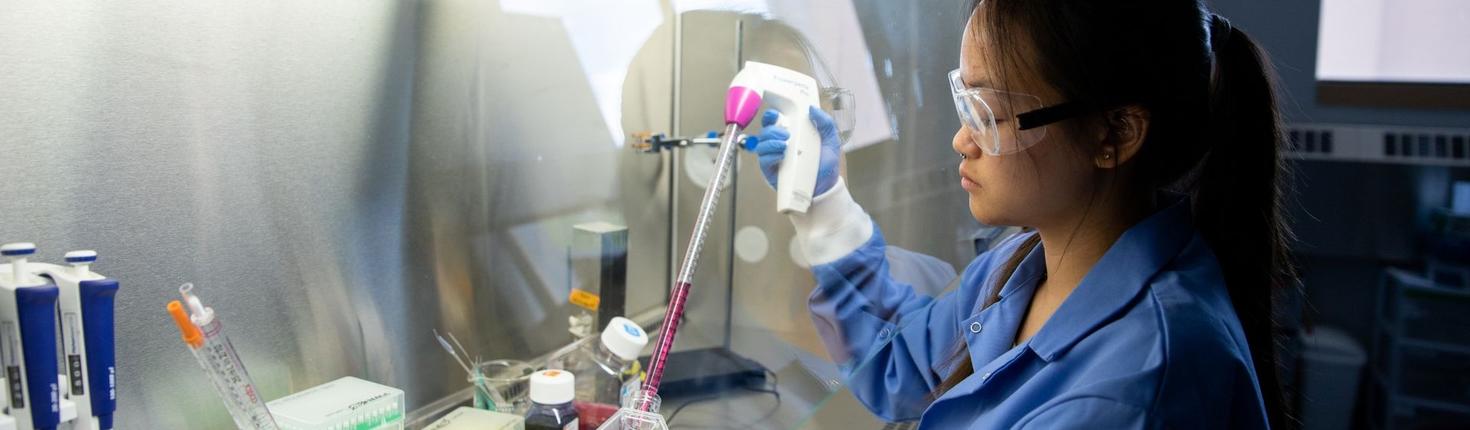 Female student working with liquid sample under a fumehood