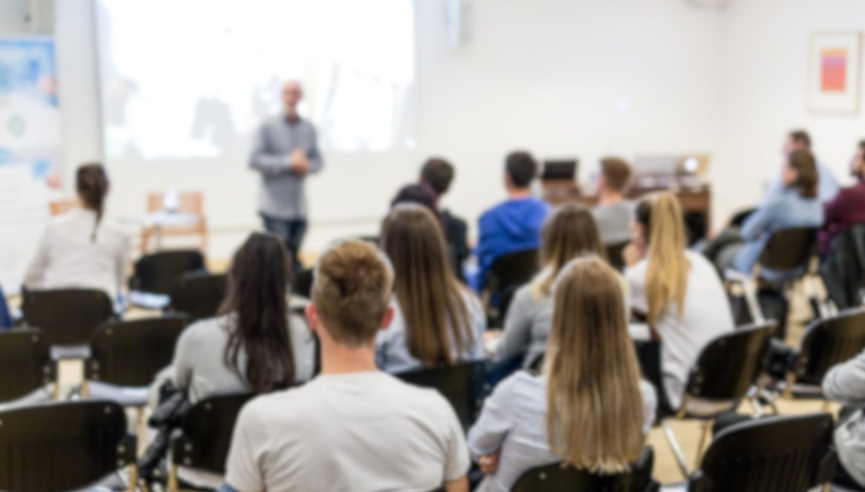 Professor talking in front of full classroom. 