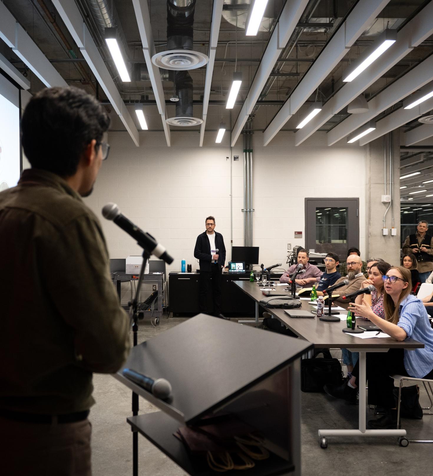 A participant giving his presentation in front of panel and crowd.