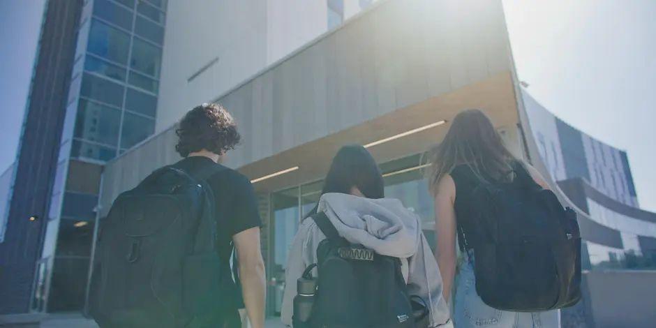 Three students walking into the 200 Lees building