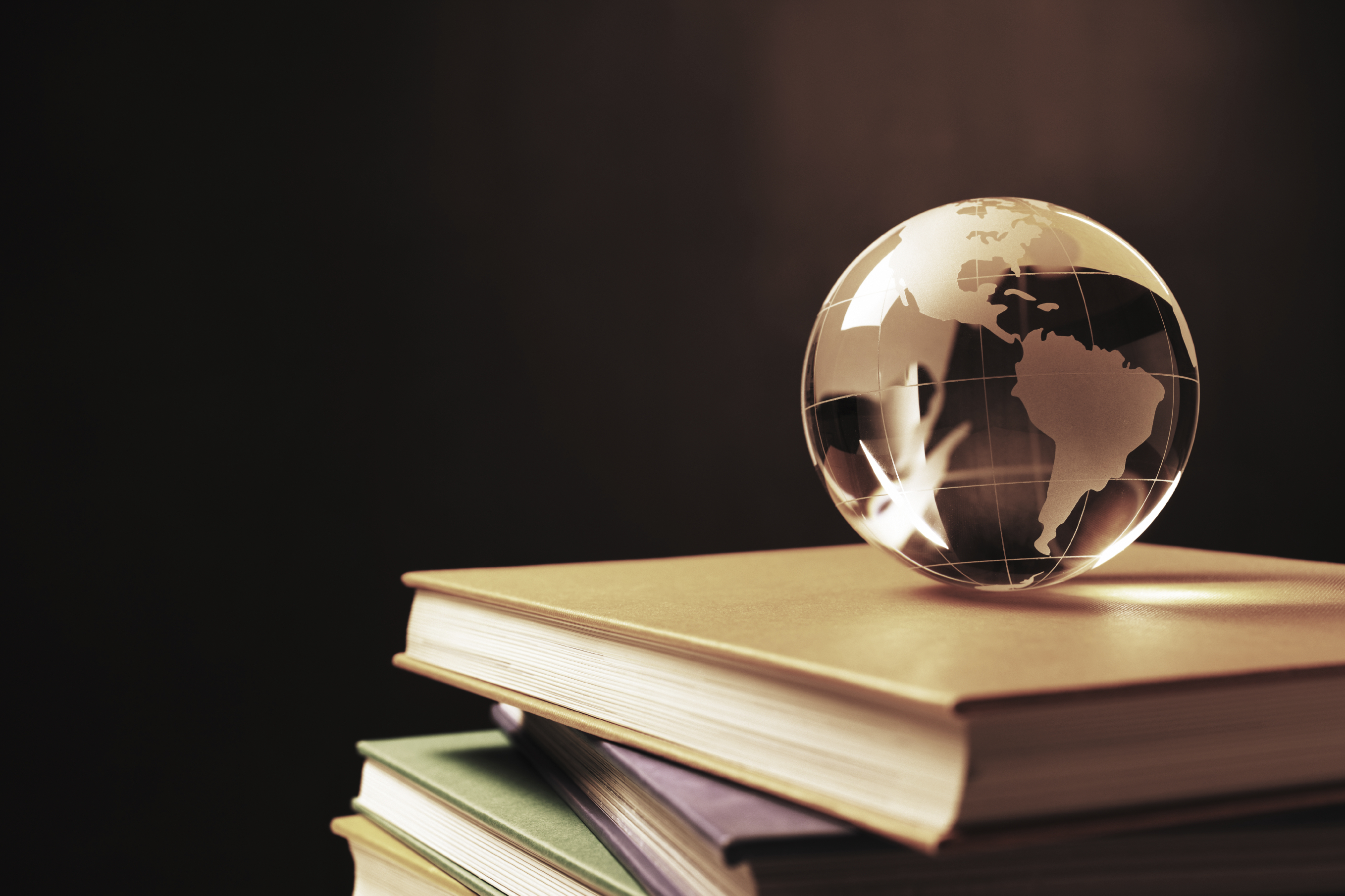 A small clear globe on top of a stack of books.