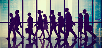 Silhouettes of people walking in the same direction. 