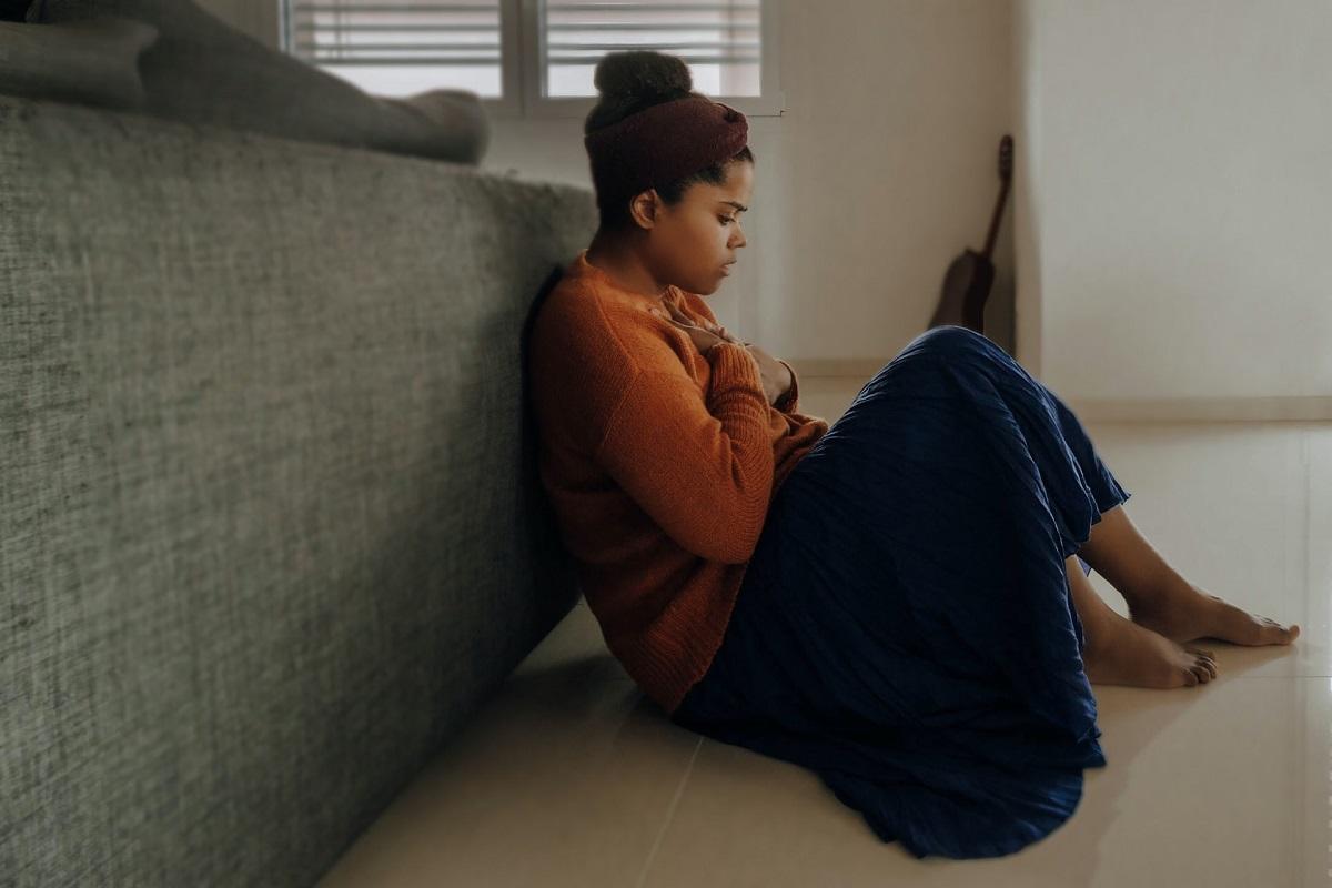 Woman huddled on ground behind couch