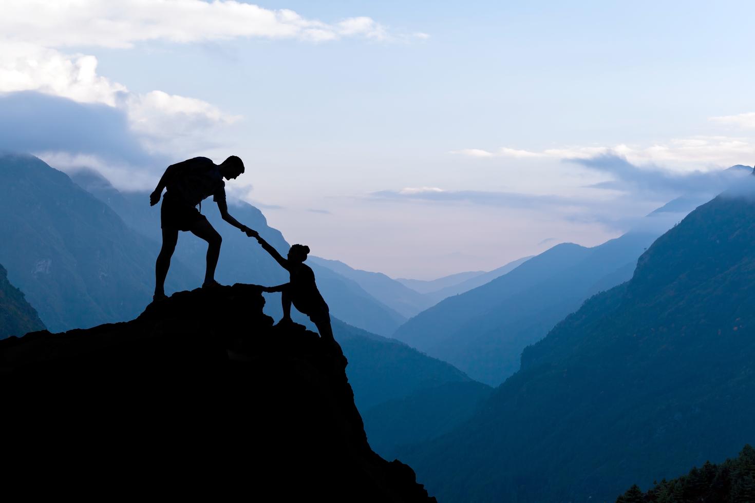 A couple of mountain climbers helping each other.