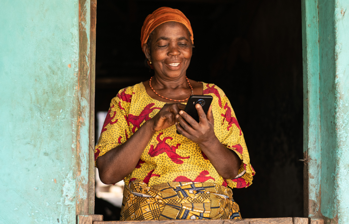 A smiling elderly African woman using her mobile phone